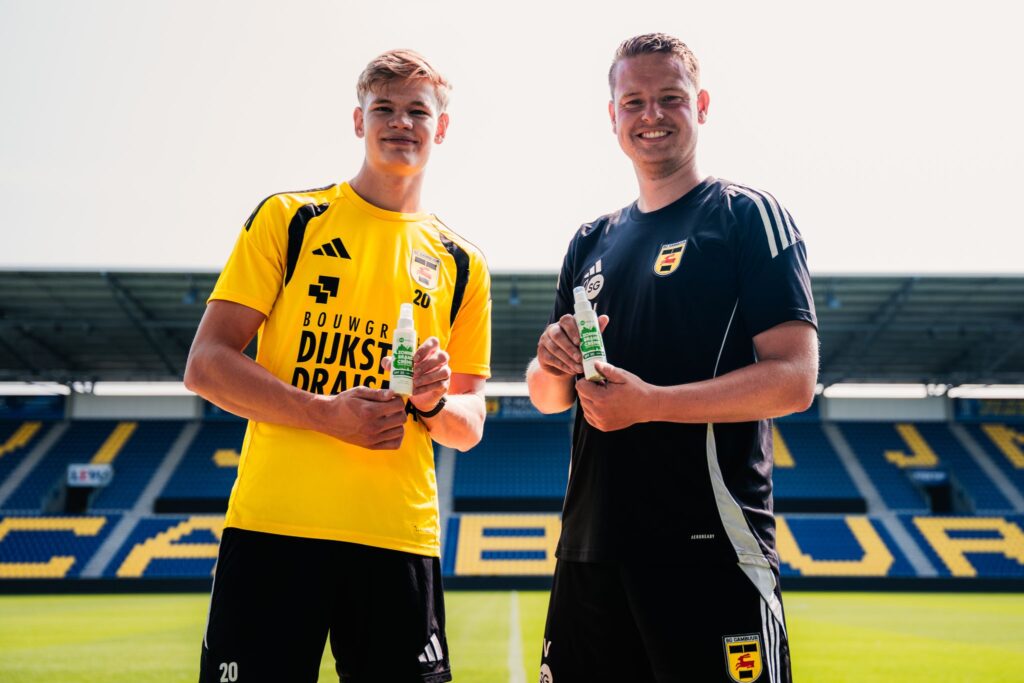 Zwei Mitglieder des niederländischen Fußballclubs SC Cambuur halten Sonnencreme in eigenem Design im Stadion