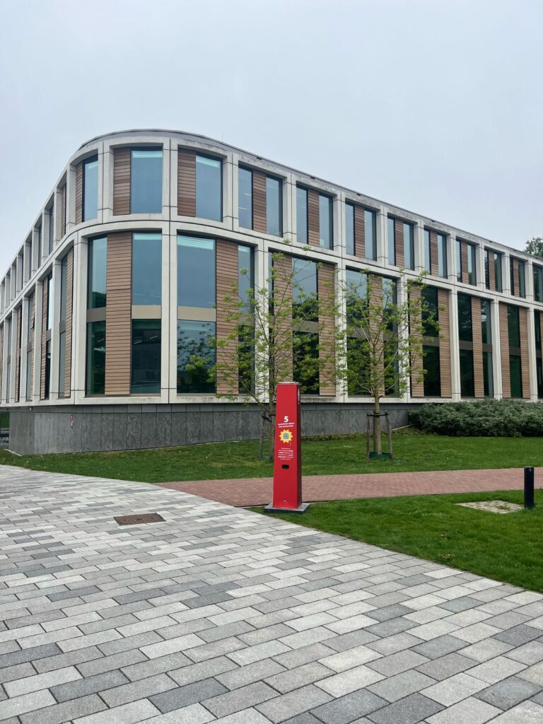 Rote Sonnencreme-Station der Radboud-Universität mit kostenloser Sonnencreme vor einem modernen Universitätsgebäude auf dem Campus in Nimwegen